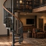 American Industrial spiral staircase with a wood handrail in a barndominium home library loft with built-in bookshelves
