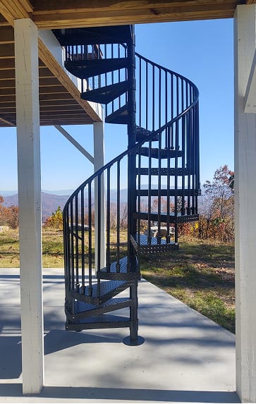 Black Builder Standard Spiral series staircase with diamond-plate steel treads on a covered porch, overlooking a mountain view