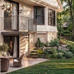 Outdoor Half Turn spiral staircase connecting a stone patio to a second-floor balcony, with dark metal treads and spindle railing.