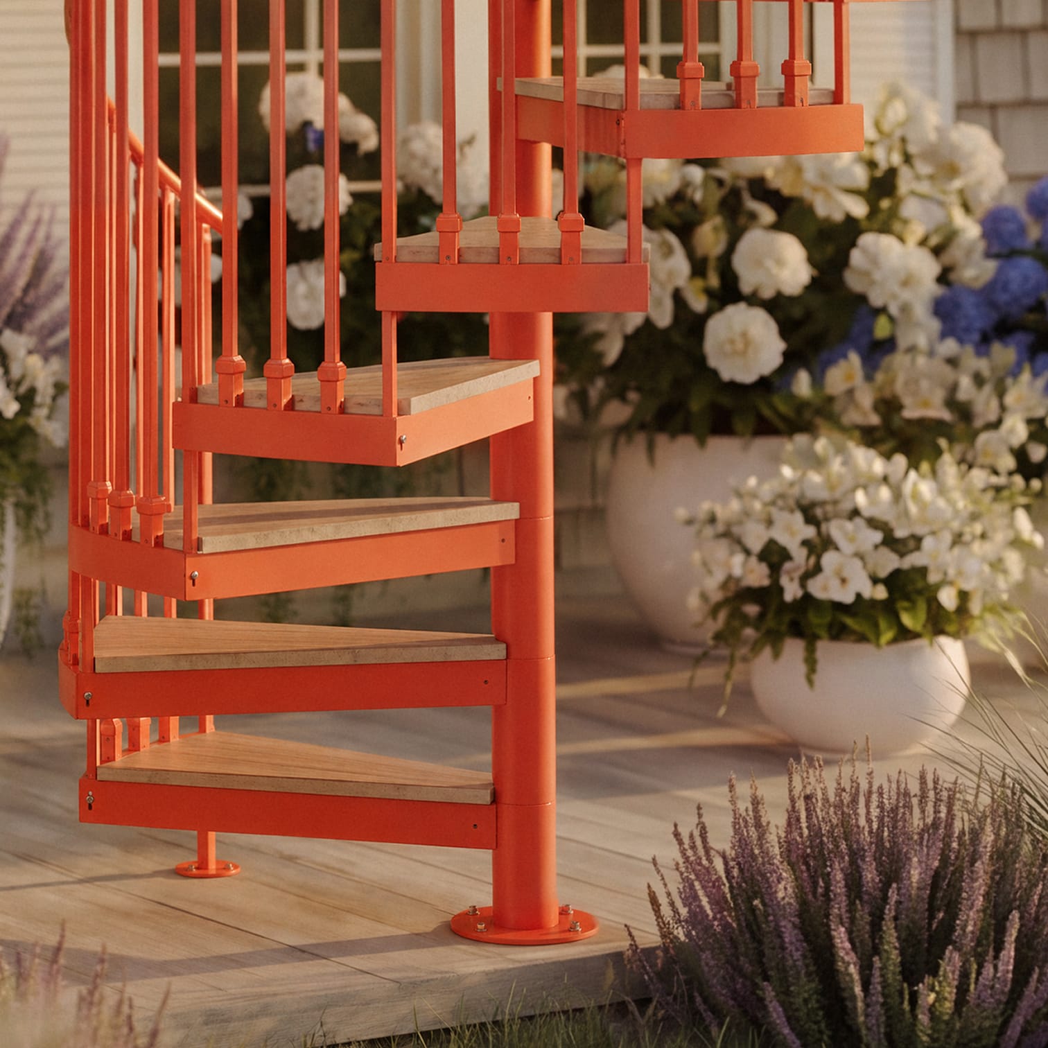 Close-up of an orange spiral staircase with wood tread inserts on a deck surrounded by potted flowers and lavender