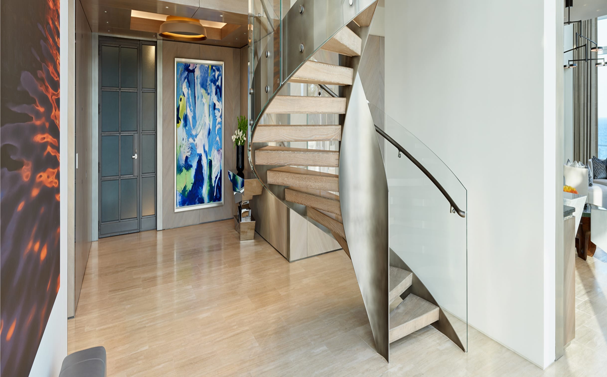 Floating wood-tread staircase with glass railing in a modern coastal entryway