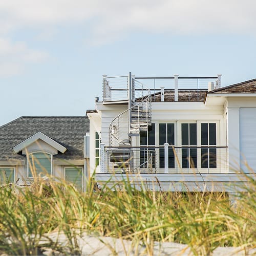 Outdoor spiral staircase in a white finish on a beach house, connecting a deck to a rooftop terrace