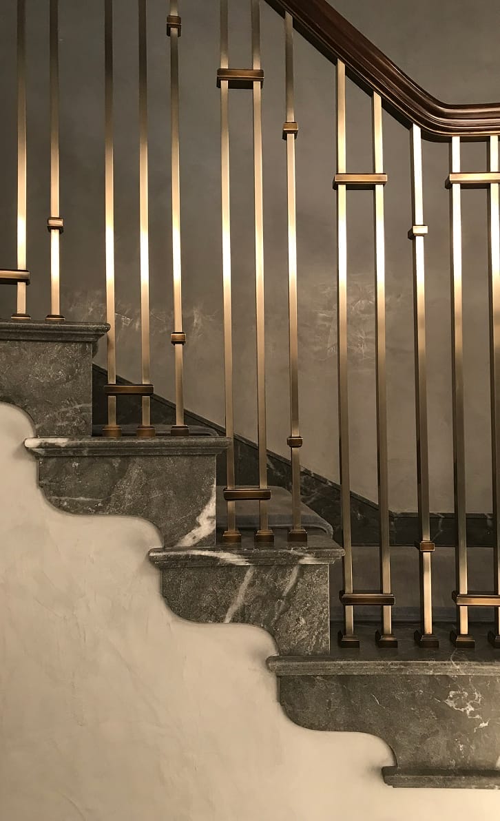 Custom bronze stair railing with square collar spindles and carved stone treads