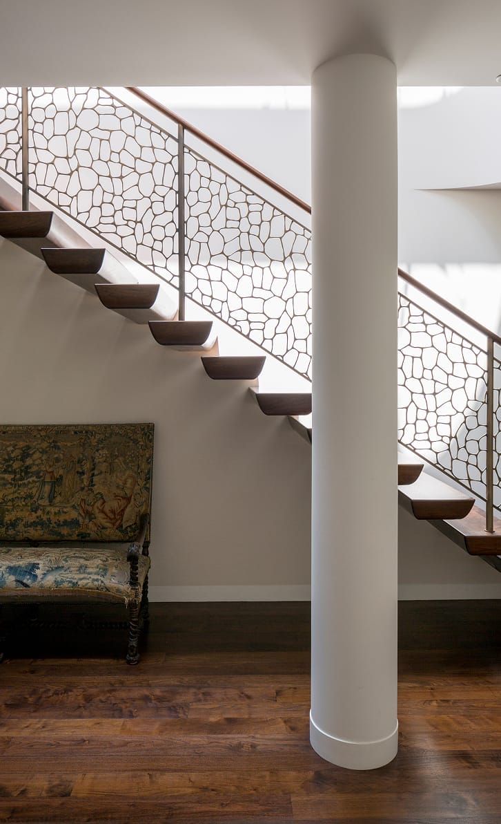 Floating wood stair treads with custom bronze lattice railing panel
