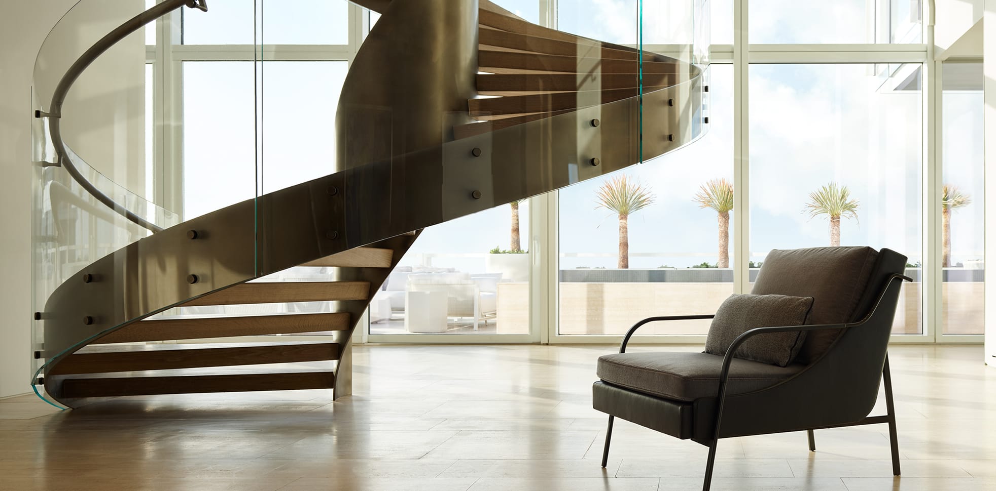 Full view of a custom curved floating staircase with glass railing and wood treads