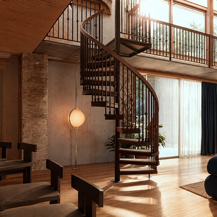 Bronze metal spiral staircase with wood treads and handrail connecting two floors of a modern living room with floor-to-ceiling windows
